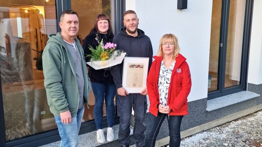 Bauherren mit Bauleiter und Hausverkäuferin vor ihrem Haus