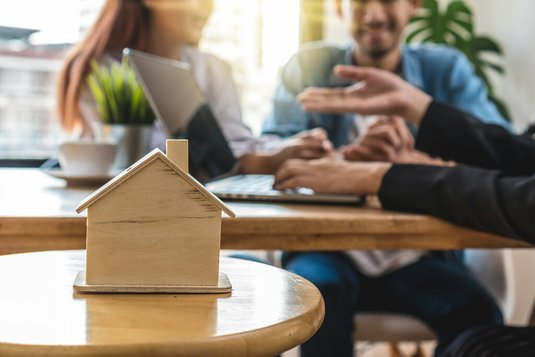 verkauf-verkaufsgespraech-beratung-bauberater-21 Ein Paar lässt sich zum Thema Hausbau beraten. Im Vordergrund ist ein Hausmodell zu sehen.