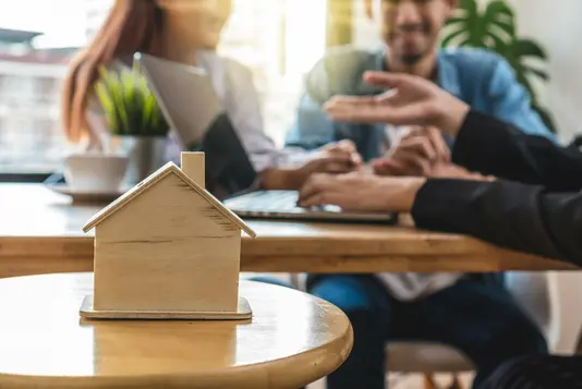 verkauf-verkaufsgespraech-beratung-bauberater-21 Ein Paar lässt sich zum Thema Hausbau beraten. Im Vordergrund ist ein Hausmodell zu sehen.